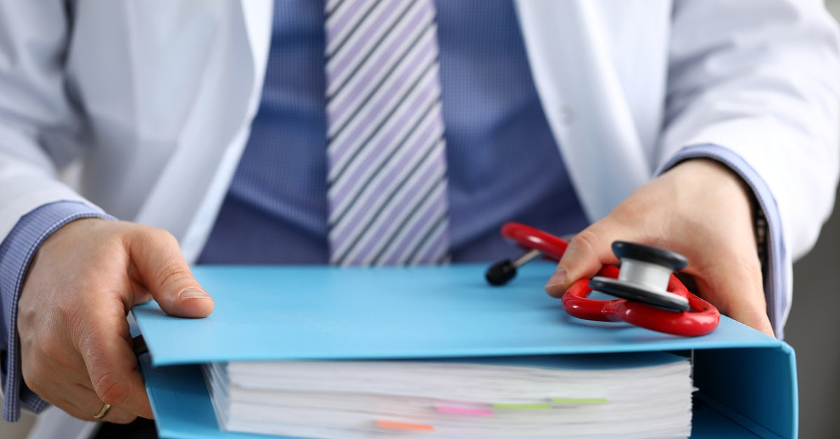 A person holding a blue binder. The binder is divided into sections by tabs and is filled with papers.
