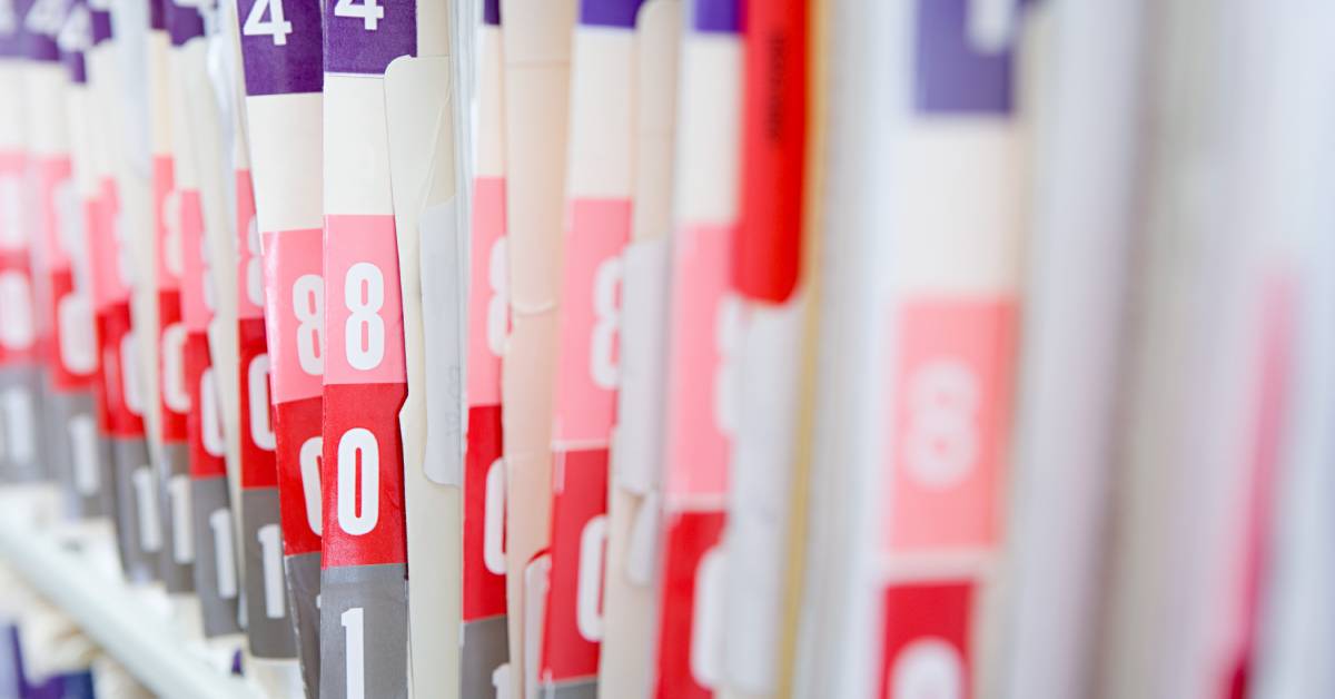 Color-coded and numbered patient files are lined up. The colors are pink, purple, and pink-ish red.
