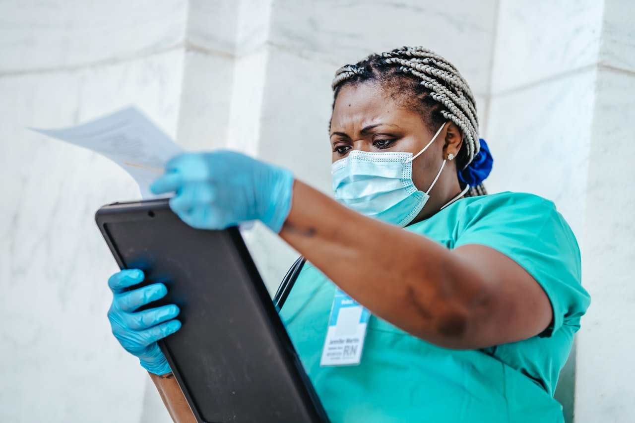 A nurse in a mask looking at a clipboard